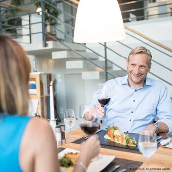 Pärchen genießt Mittagessen in Bad Aibling und stößt mit Glas Rotwein an