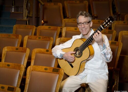 Eliot Fisk in Hörsaal mit weißem Hemd und Gitarre