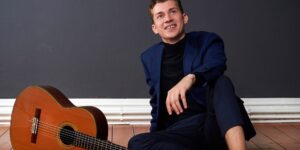 Gitarrist Thibaut Garcia sitzt auf Holzboden neben Gitarre